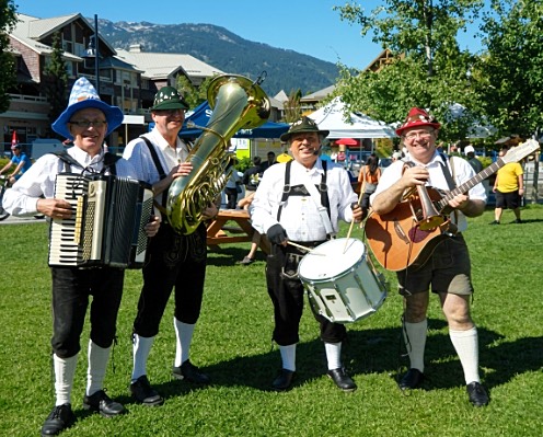 Gary Wenzlaff with three other musicians in Bavarian dress — tuba, snare drum and guitar — at an outdoor festival.
