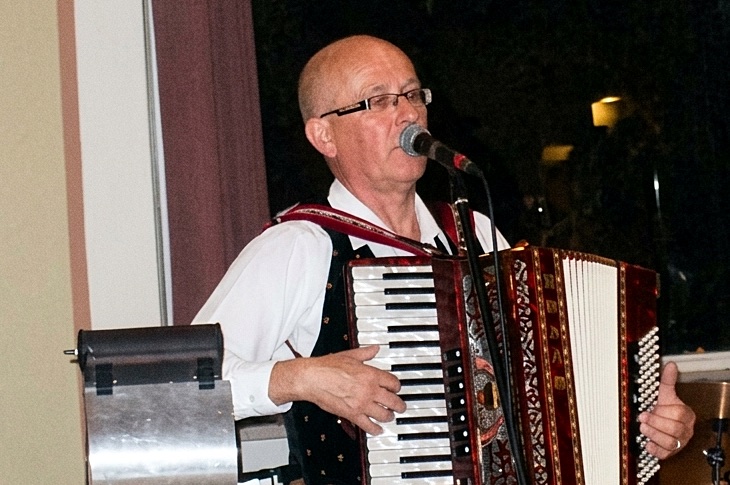 Gary Wenzlaff alone on a small stage with a microphone and his accordion.