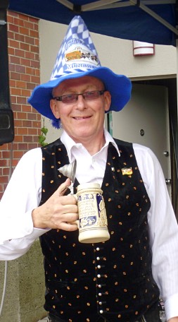Gary Wenzlaff in a blue-and-white Bavarian hat holding a stoneware beer stein.
